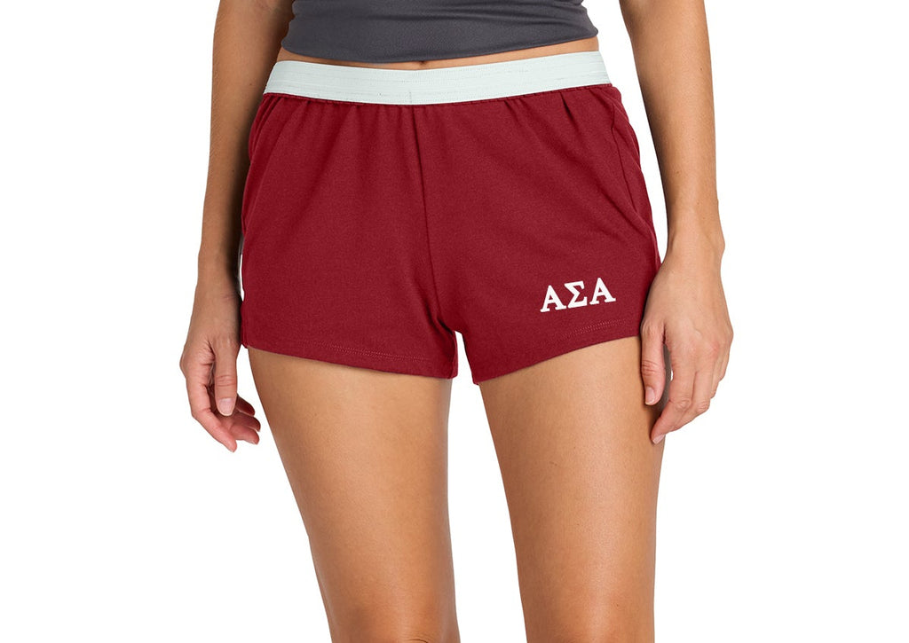 Person wearing maroon shorts with a logo on a white background